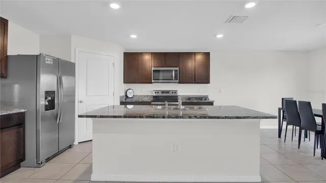 a kitchen with stainless steel appliances granite countertop a sink and a refrigerator