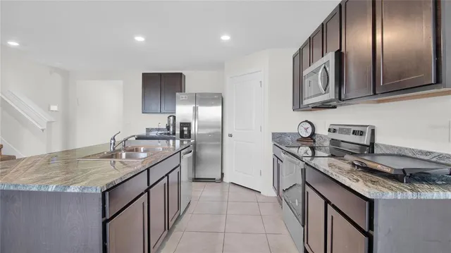 a kitchen with stainless steel appliances granite countertop a sink a stove and a refrigerator