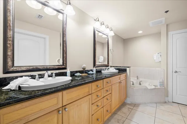 a bathroom with a double vanity sink a mirror and a bathtub