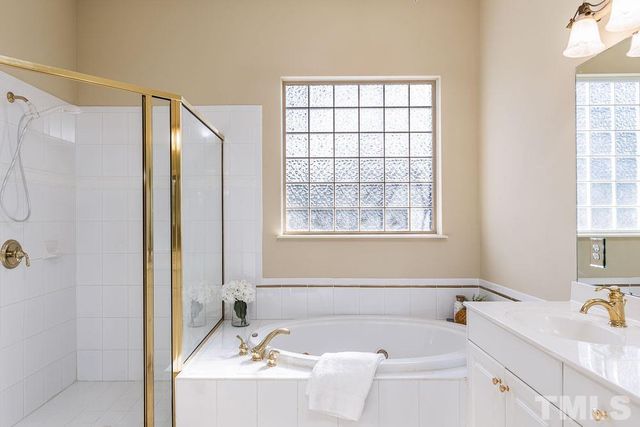 a bathroom with a tub sink and mirror next to a window