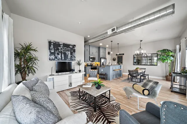 a living room with furniture kitchen view and a large window