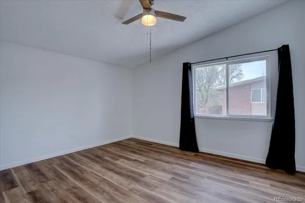 a view of empty room with wooden floor and fan