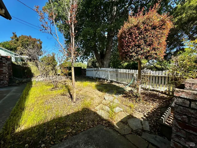 an empty room with wooden floor a fireplace a ceiling fan and windows