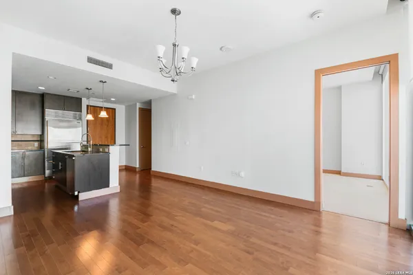 a view of a hallway with wooden floor and a kitchen