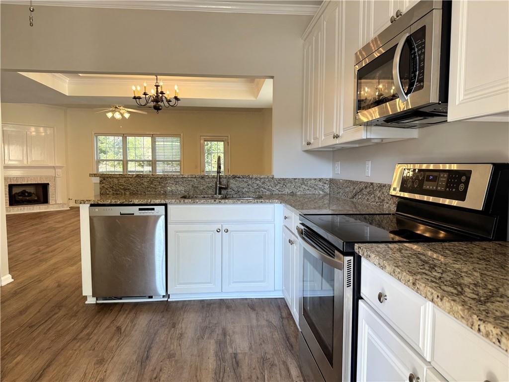 2075 Pine Tree Drive Buford, GA 30518 - Photo 6 of 18 a kitchen with stainless steel appliances granite countertop a sink a stove a microwave and wooden cabinets