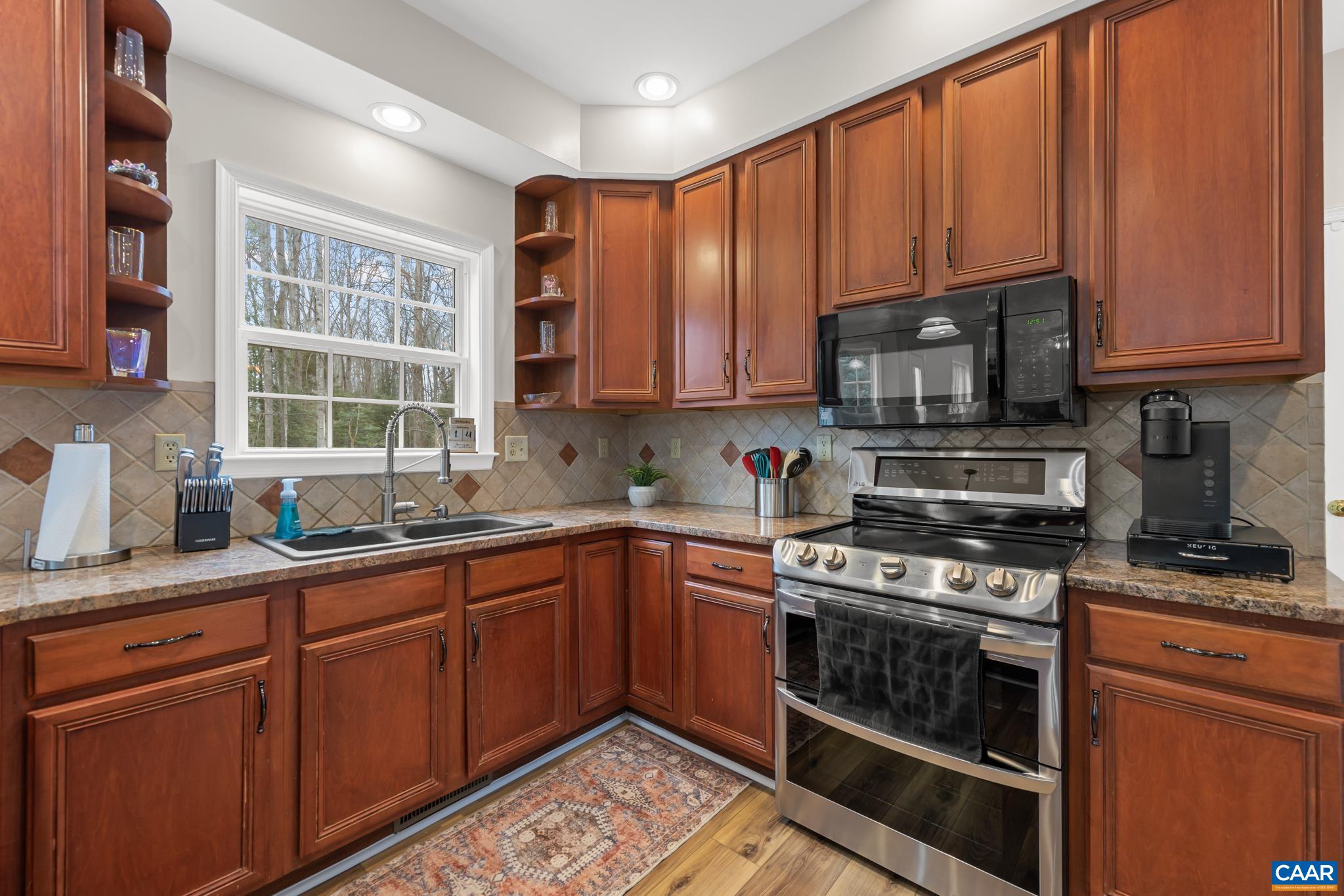 334 Carodon Drive Ruckersville, VA 22968 - Photo 19 of 54 a kitchen with stainless steel appliances granite countertop a stove a sink dishwasher and a microwave oven with cabinets