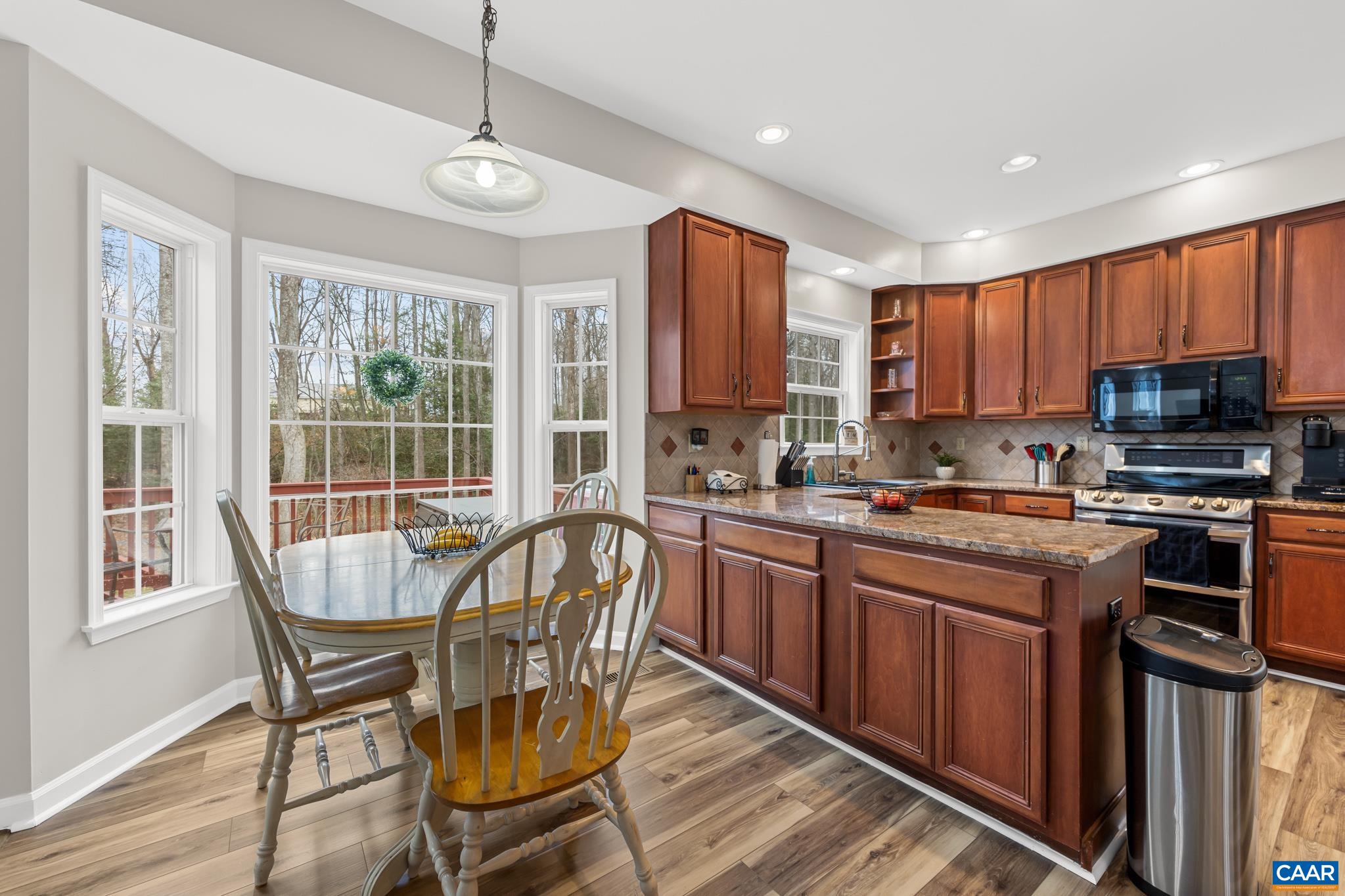 334 Carodon Drive Ruckersville, VA 22968 - Photo 21 of 54 a open kitchen with stainless steel appliances granite countertop a stove top oven a sink dishwasher a dining table and chairs with wooden floor