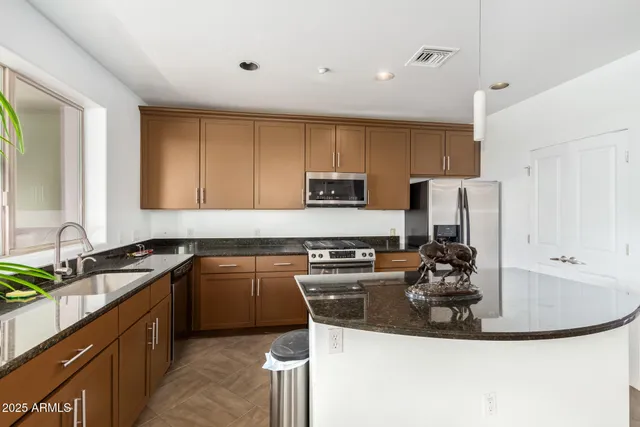 a kitchen with kitchen island granite countertop a sink stove and refrigerator