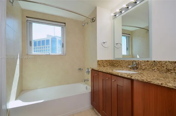 a bathroom with a granite countertop sink and a bathtub