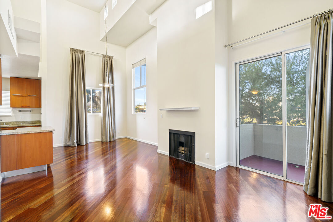 2045 Beloit Avenue, Unit 306 Los Angeles, CA 90025 - Photo 2 of 14 a view of empty room with wooden floor and a fireplace