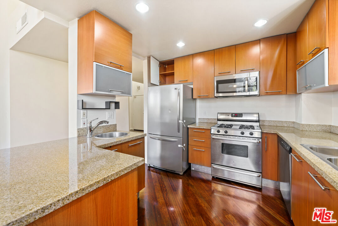 2045 Beloit Avenue, Unit 306 Los Angeles, CA 90025 - Photo 4 of 14 a kitchen with stainless steel appliances granite countertop a refrigerator a stove and a sink with wooden floor
