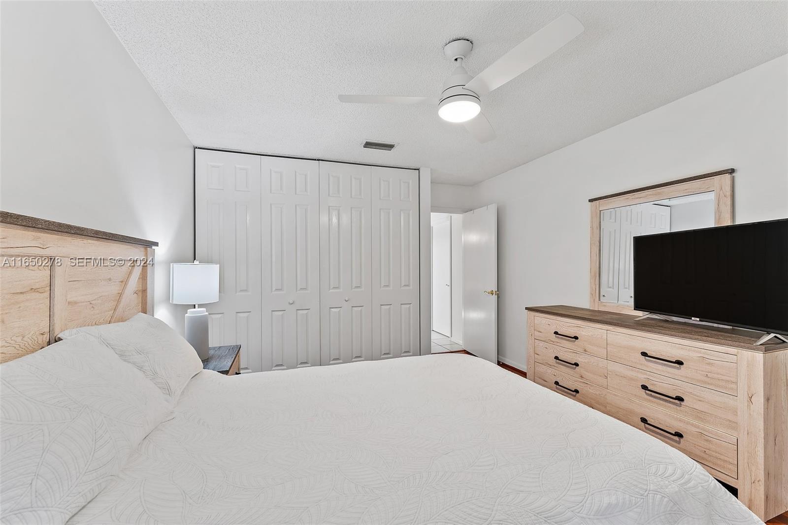 101 Sand Pine Drive, Unit 101 Jupiter, FL 33477 - Photo 36 of 47 a bedroom with a bed and a flat screen tv