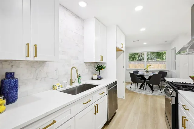 a kitchen with a sink dishwasher stove and white cabinets