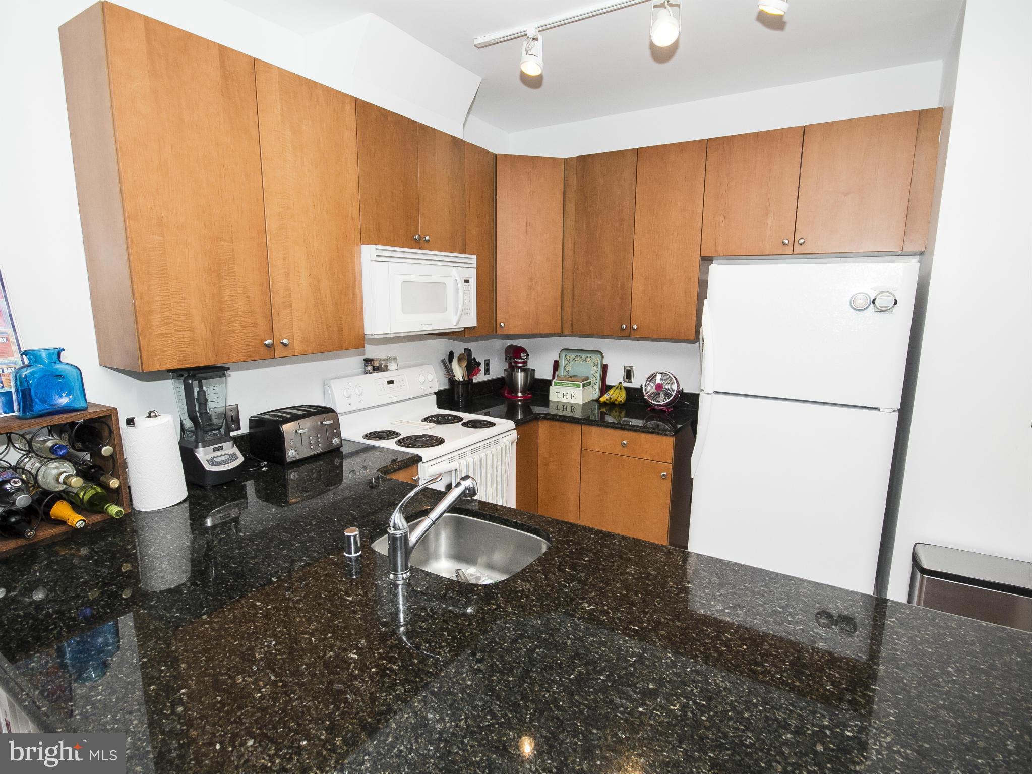 2007 Clipper Park Road, Unit 116 Baltimore, MD 21211 - Photo 3 of 30 a kitchen with a refrigerator a stove a sink dishwasher and a dining table with wooden floor