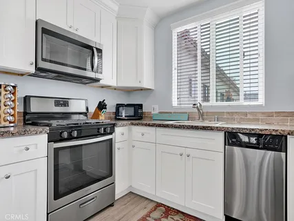 a kitchen with granite countertop white cabinets and stainless steel appliances