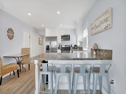 a large kitchen with granite countertop lots of white furniture and stainless steel appliances