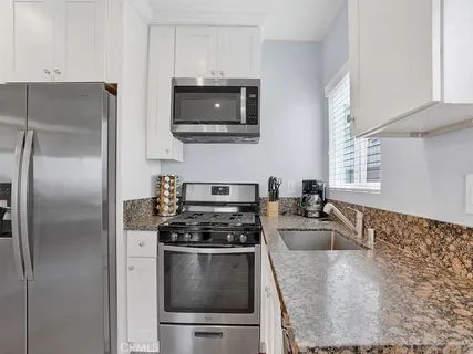 a kitchen with stainless steel appliances granite countertop a refrigerator stove top oven and sink