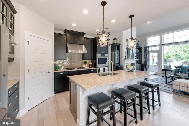 a kitchen with stainless steel appliances kitchen island granite countertop a table chairs and a wooden floors