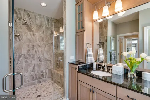 a bathroom with a granite countertop sink a mirror a vanity and a shower