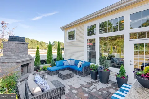 a view of a patio with couches chairs potted plants and floor to ceiling window and potted plants