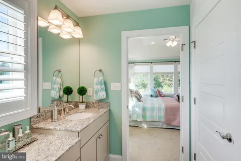 a bathroom with a granite countertop sink and large mirror