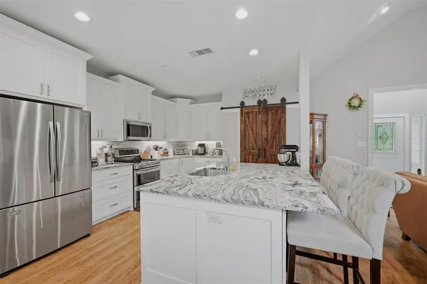 a kitchen with stainless steel appliances granite countertop a refrigerator a stove top oven a sink dishwasher and wooden cabinets with wooden floor