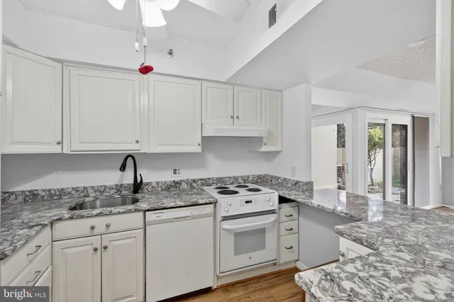 a kitchen with granite countertop a sink stainless steel appliances and cabinets