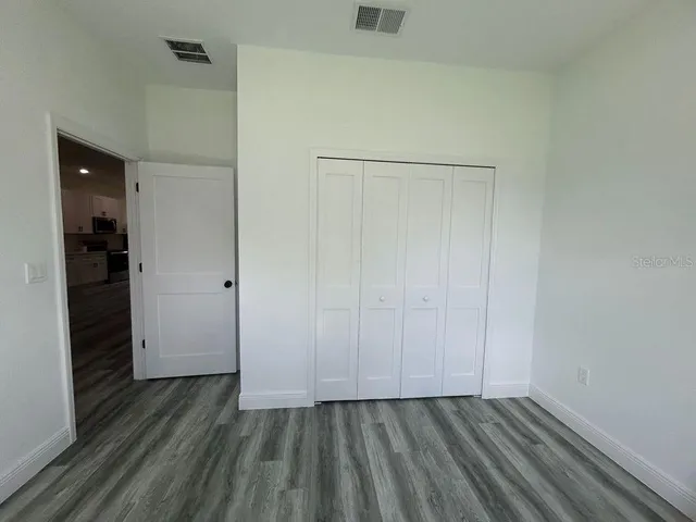 a view of an empty room with closet and wooden floor