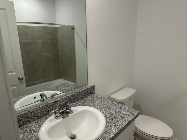 a bathroom with a granite countertop sink a toilet and a mirror