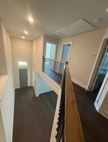 a view of an empty room with wooden floor and windows