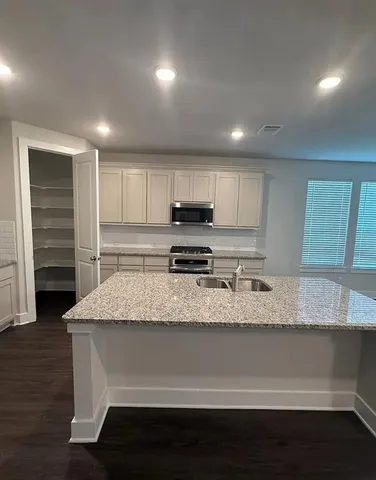 a kitchen with granite countertop a refrigerator and a stove top oven