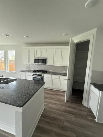 a kitchen with granite countertop sink and wooden floor