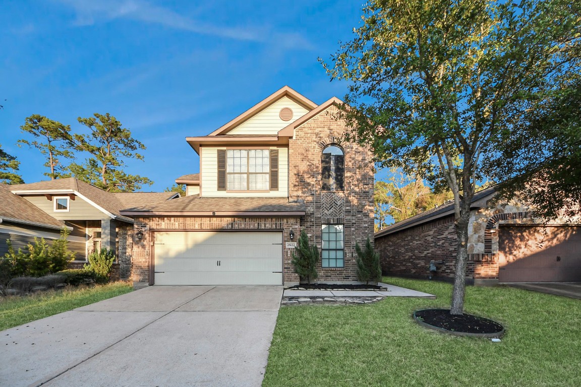 a view of a house with a yard and a large tree