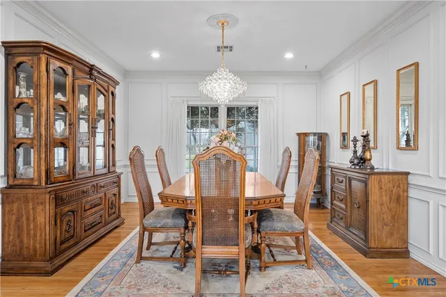 a dining room with furniture a chandelier and wooden floor