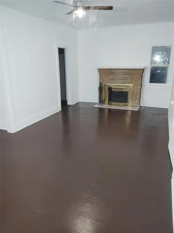 an empty room with wooden floor fireplace and a window
