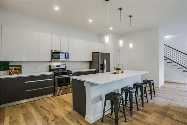 a large kitchen with kitchen island a stove a table a sink and a refrigerator