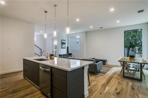 a kitchen with a sink a counter top space and living room view