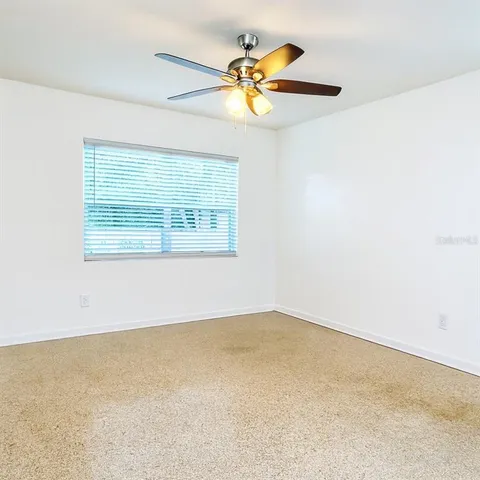 an empty room with a window and a ceiling fan