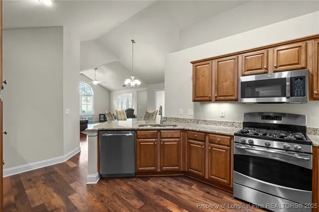 a kitchen with stainless steel appliances granite countertop a stove top oven a sink dishwasher and a microwave oven with wooden floor