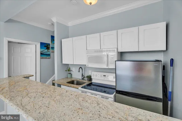 a kitchen with stainless steel appliances granite countertop a refrigerator sink and white cabinets