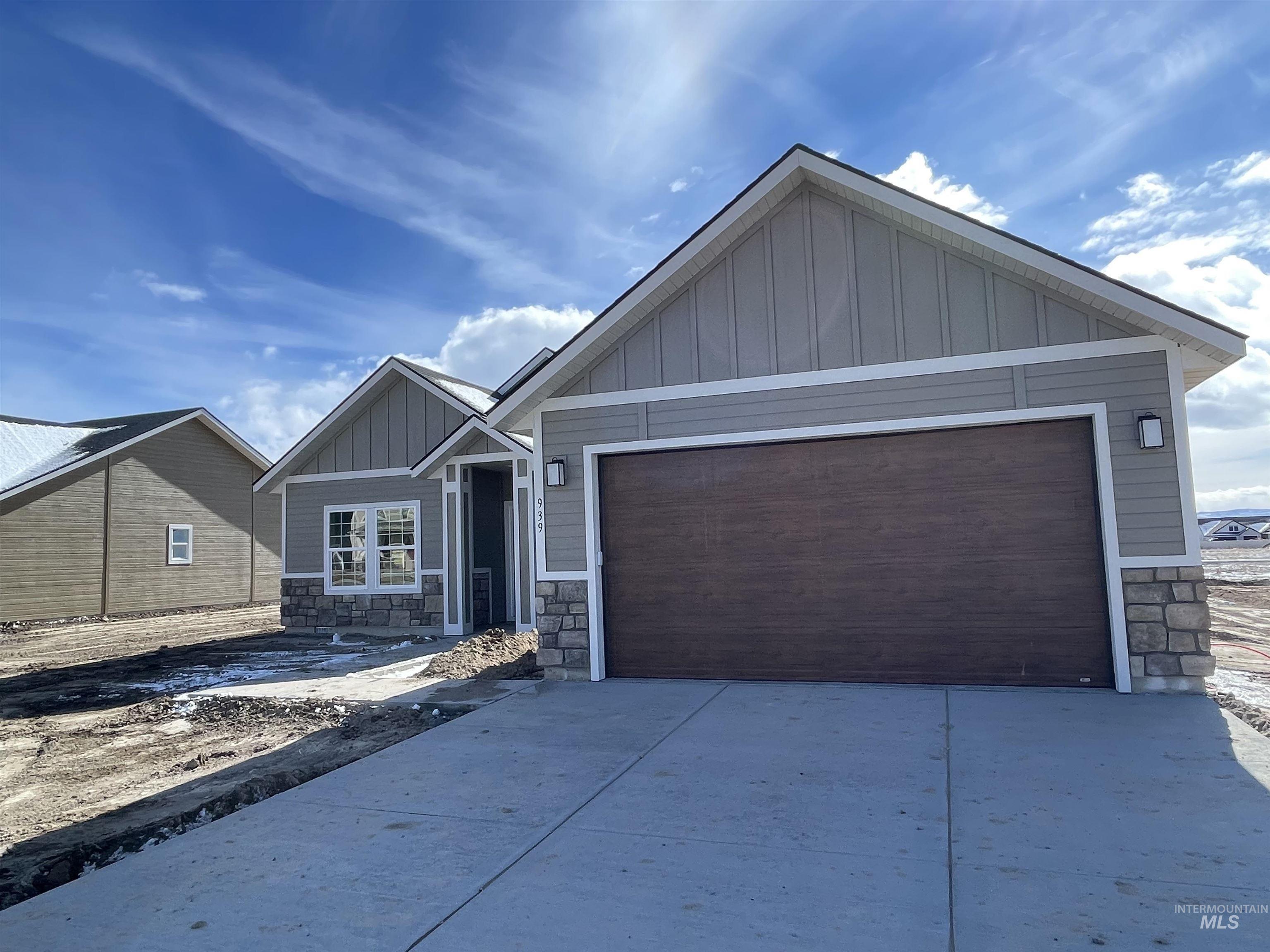 Craftsman-style house with board and batten siding, stone siding, an attached garage, and concrete driveway