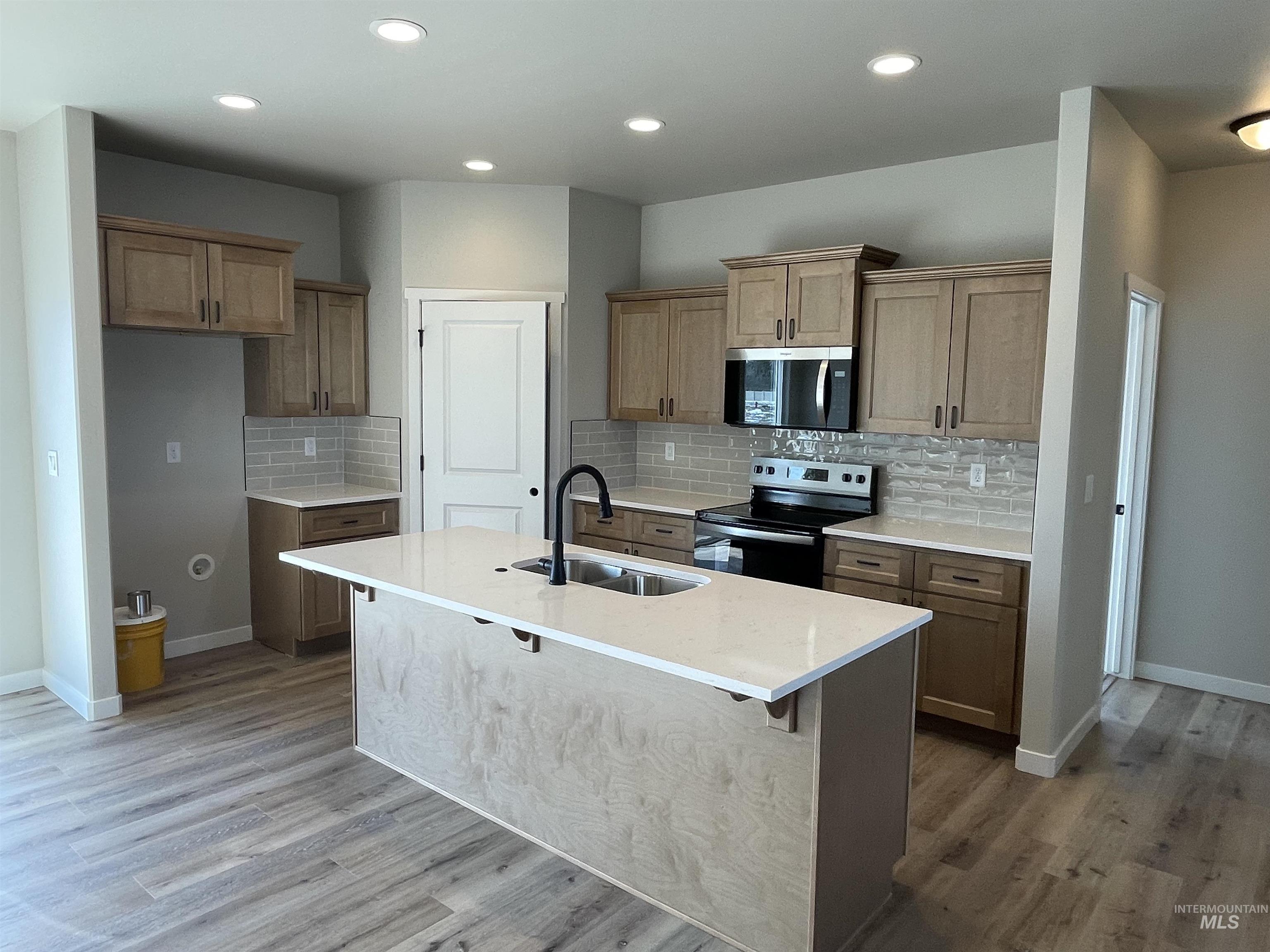 939 Quartz Road Kimberly, ID 83341 - Photo 2 of 18 Kitchen featuring stainless steel appliances, light stone counters, backsplash, a center island with sink, and recessed lighting