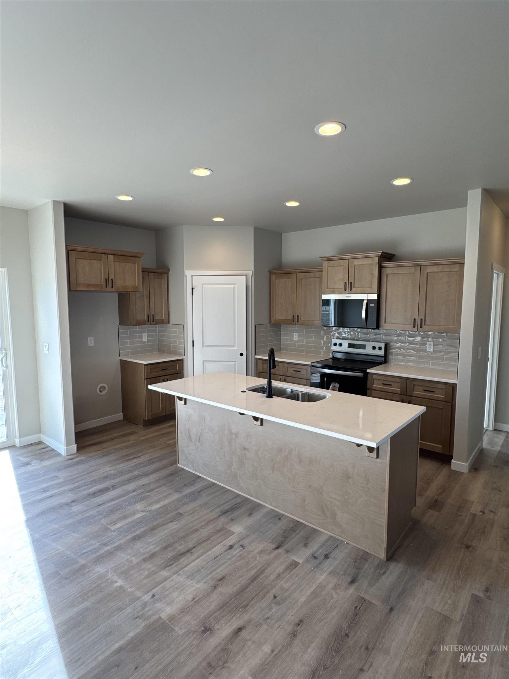 939 Quartz Road Kimberly, ID 83341 - Photo 3 of 18 Kitchen with decorative backsplash, stainless steel appliances, a kitchen breakfast bar, a kitchen island with sink, and dark wood-style floors