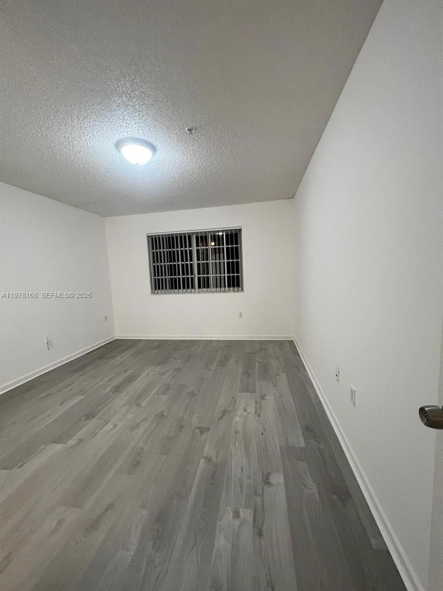 2173 Renaissance Boulevard, Unit 201 Miramar, FL 33025 - Photo 6 of 12 an empty room with wooden floor and windows