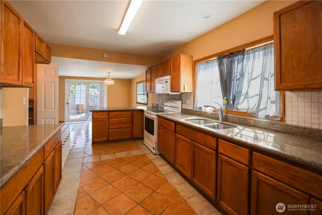 a large kitchen with kitchen island granite countertop a large window and a sink