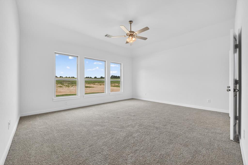 416 McAlpine Drive Springtown, TX 76082 - Photo 21 of 40 Spacious room featuring light-toned carpeting, white walls, and three large windows offering expansive outdoor scenery