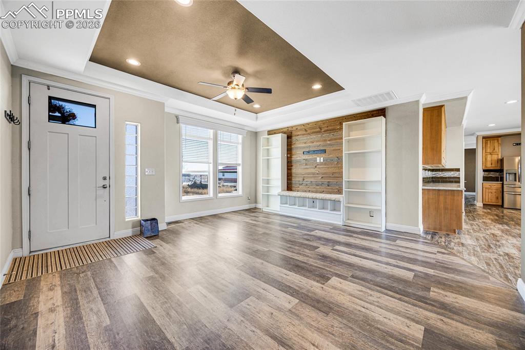 7880 J D Johnson Road Peyton, CO 80831 - Photo 6 of 50 Unfurnished living room with ceiling fan, crown molding, wood finished floors, a raised ceiling, and recessed lighting