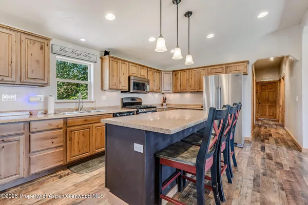 a kitchen with stainless steel appliances granite countertop a table chairs sink refrigerator and cabinets