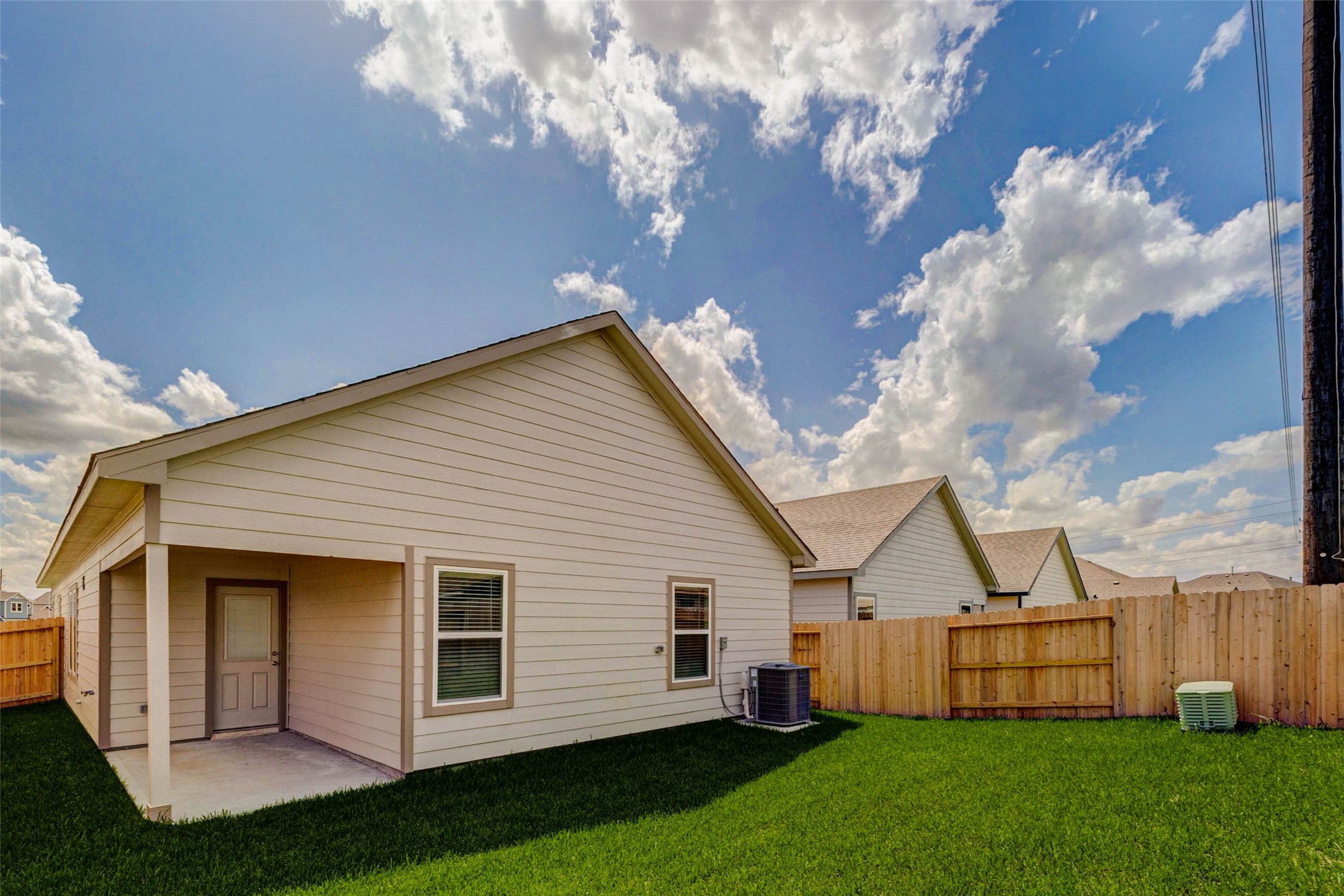 6467 Escondido Drive Rosharon, TX 77583 - Photo 31 of 32 Wide backyard view featuring a covered patio, rear door, private wood fencing, fresh lawn, and open sky. The yard offers a comfortable outdoor area for grilling, seating, gardening, or play, while the covered patio provides shade and a natural spot to enjoy morning coffee or evening relaxation.