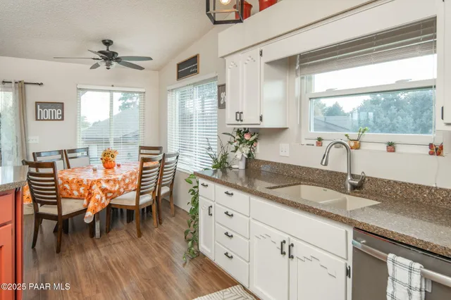 a dining hall with stainless steel appliances granite countertop a table chairs and a large window